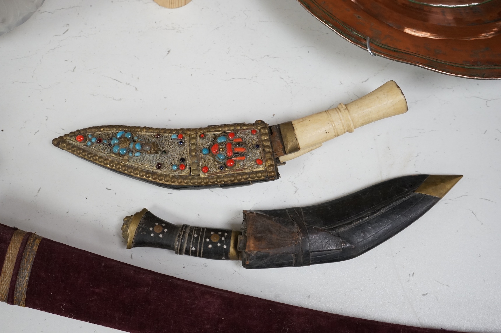 An Indian Tulwar sword, in scabbard and two small kukri, largest 93cm long.